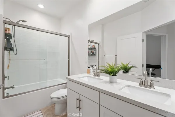 a bathroom with a granite countertop sink a toilet a mirror a shower and vanity