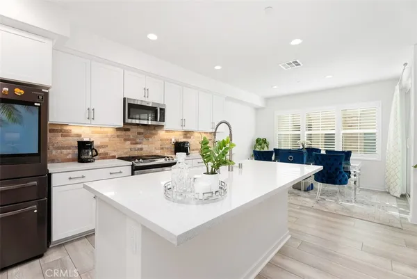 a kitchen with stainless steel appliances wooden floor dining table and chairs