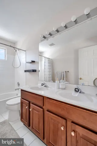 a spacious bathroom with a double vanity sink toilet mirror and bathtub