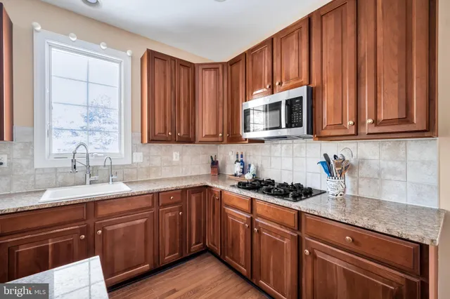 a kitchen with stainless steel appliances granite countertop a sink dishwasher stove and cabinets with wooden floor