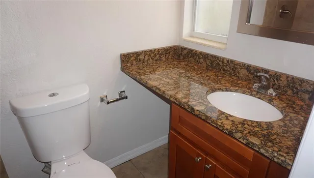 a bathroom with a granite countertop sink and a toilet