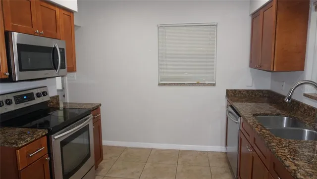 a kitchen with granite countertop a sink dishwasher stove and microwave oven