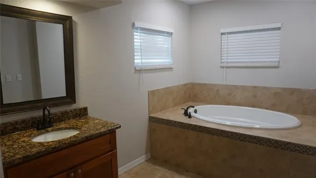 a bathroom with a granite countertop sink and a bathtub