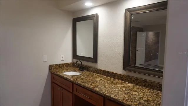 a bathroom with a granite countertop sink and a mirror