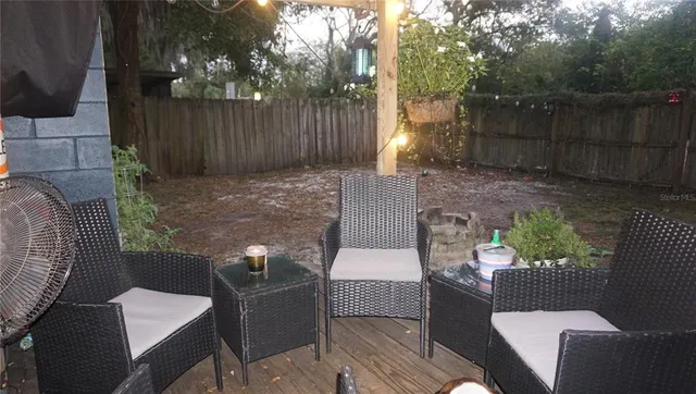 a view of a patio with couches chairs and a fire pit with wooden fence