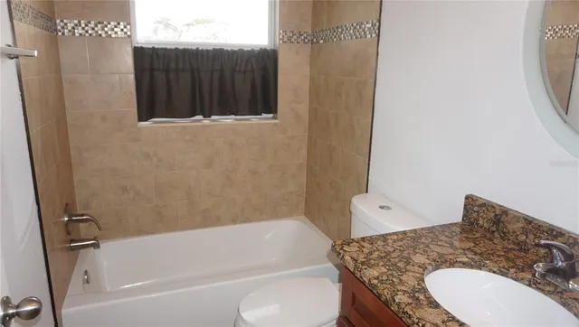 a bathroom with a granite countertop sink toilet and bathtub