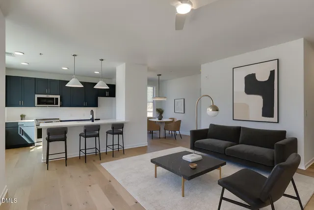 a living room with furniture kitchen view and a wooden floor