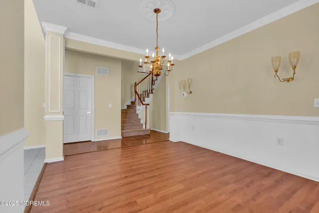 a view of a room with wooden floor and a chandelier