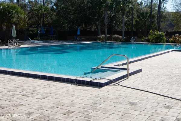a view of a swimming pool with a bench and trees