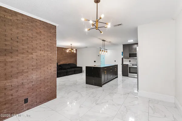 a living room with stainless steel appliances kitchen island granite countertop a rug and white cabinets