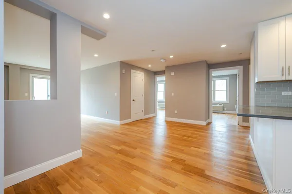 a view of an empty room with window and wooden floor