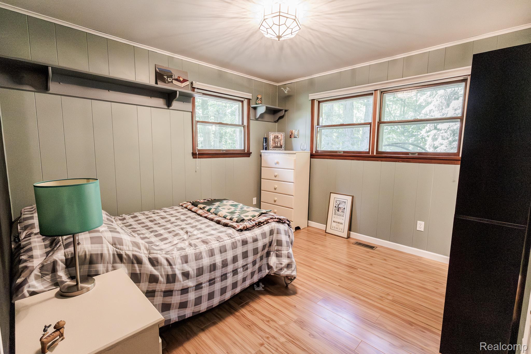 8197 Irish Road Millington, MI 48746 - Photo 23 of 38 Room featuring wood-finish flooring, two large windows with wood trim, board and batten wall detailing, a built-in overhead shelf, and a ceiling-mounted light fixture