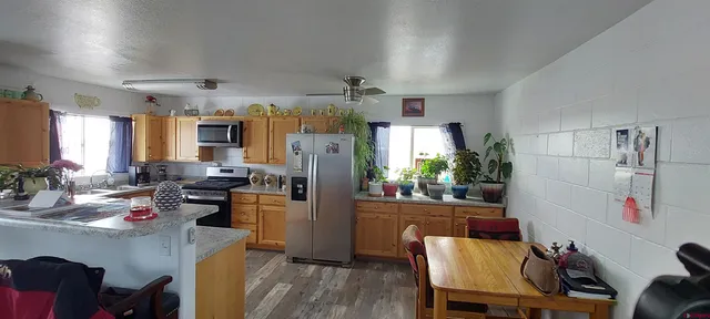 a kitchen with a refrigerator a stove a dining table and chairs with wooden floor