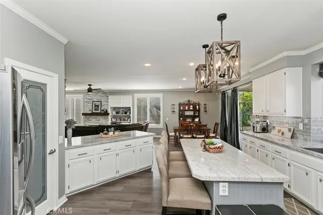 a kitchen with stainless steel appliances kitchen island granite countertop a sink dishwasher a stove a refrigerator and a dining table with wooden floor