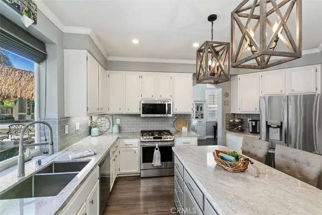 a kitchen with stainless steel appliances granite countertop a sink a stove and a wooden floors