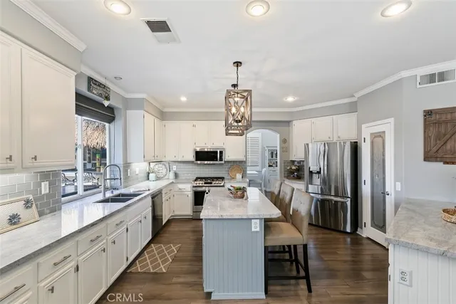 a large kitchen with kitchen island a large counter space a sink stainless steel appliances and cabinets
