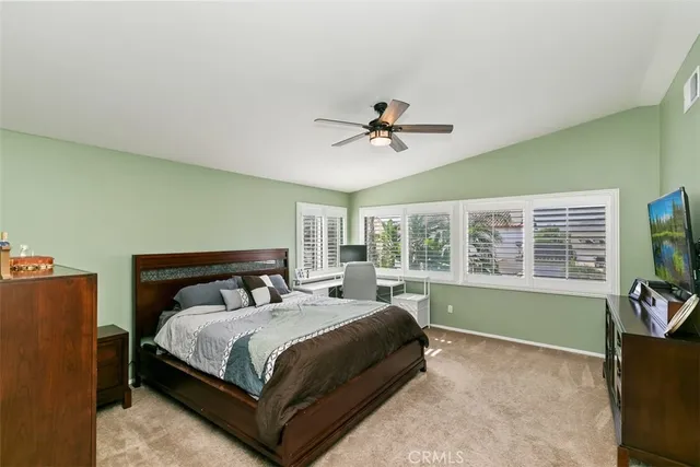 a bedroom with a bed next to a window and a flat screen tv