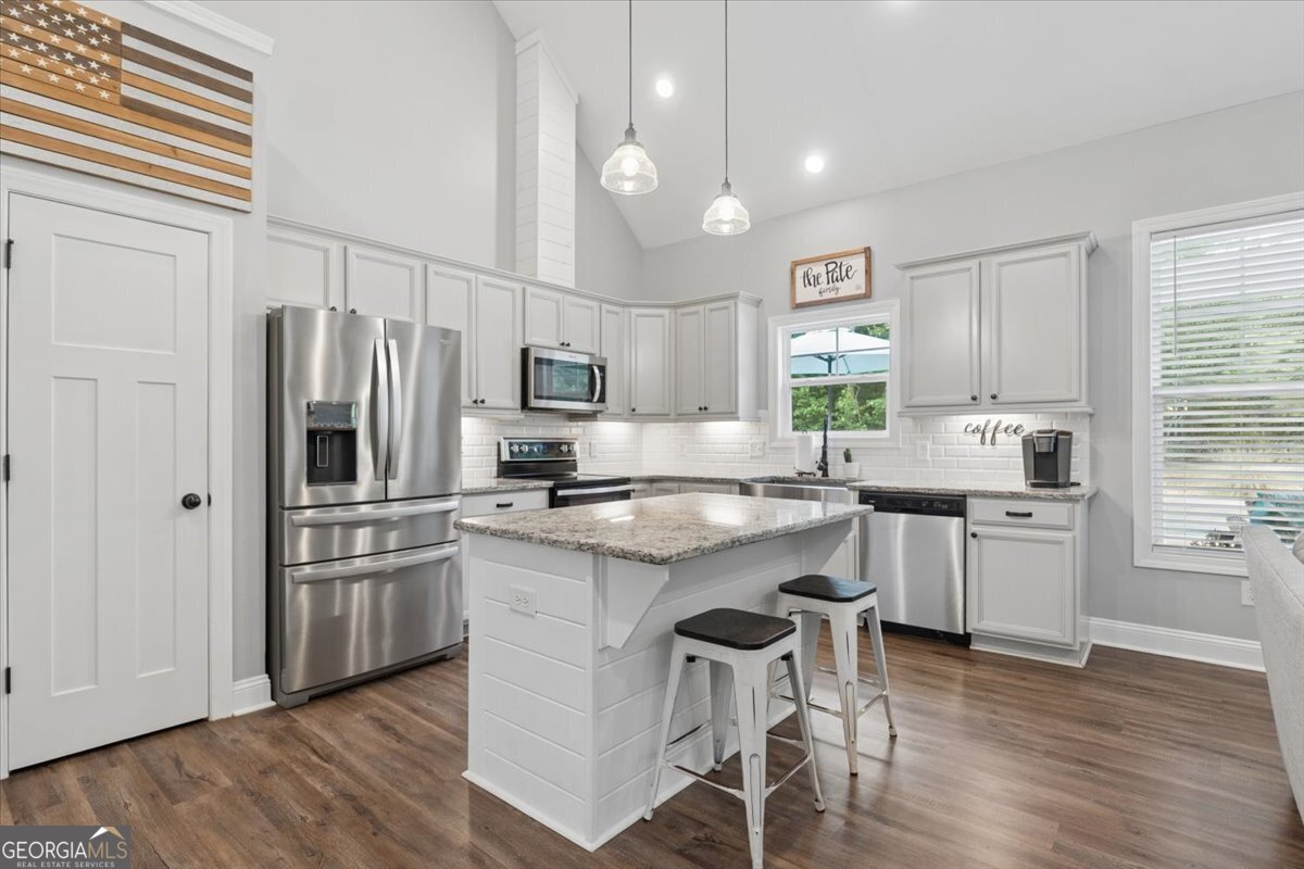683 Teagle Road Forsyth, GA 31029 - Photo 10 of 50 a kitchen with stainless steel appliances granite countertop a refrigerator a stove top oven a sink dishwasher and white cabinets with wooden floor