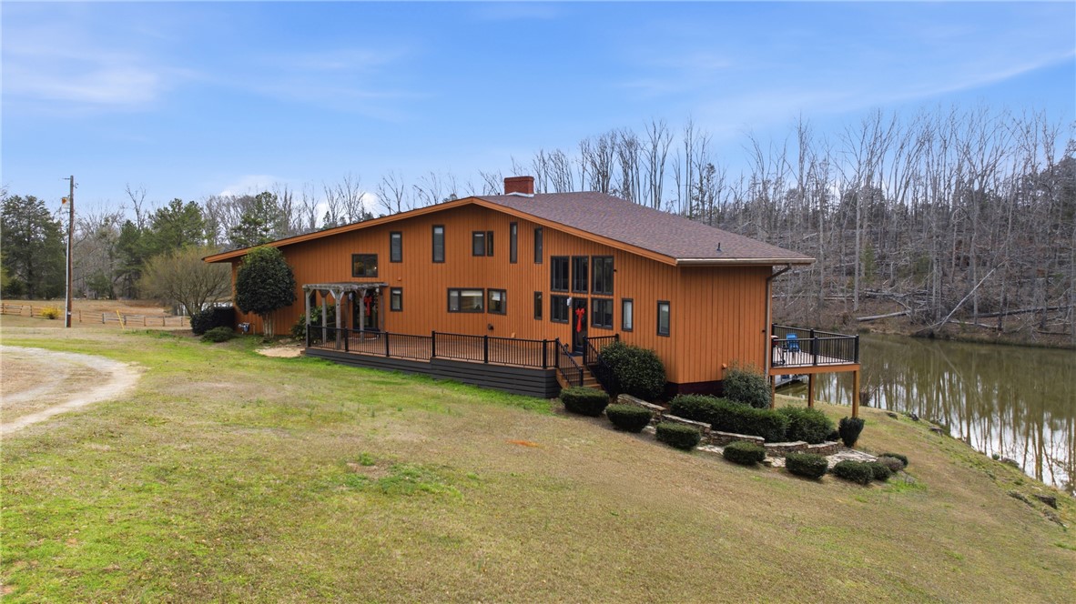 This spacious house features an inviting deck overlooking a serene lake and expansive grounds.