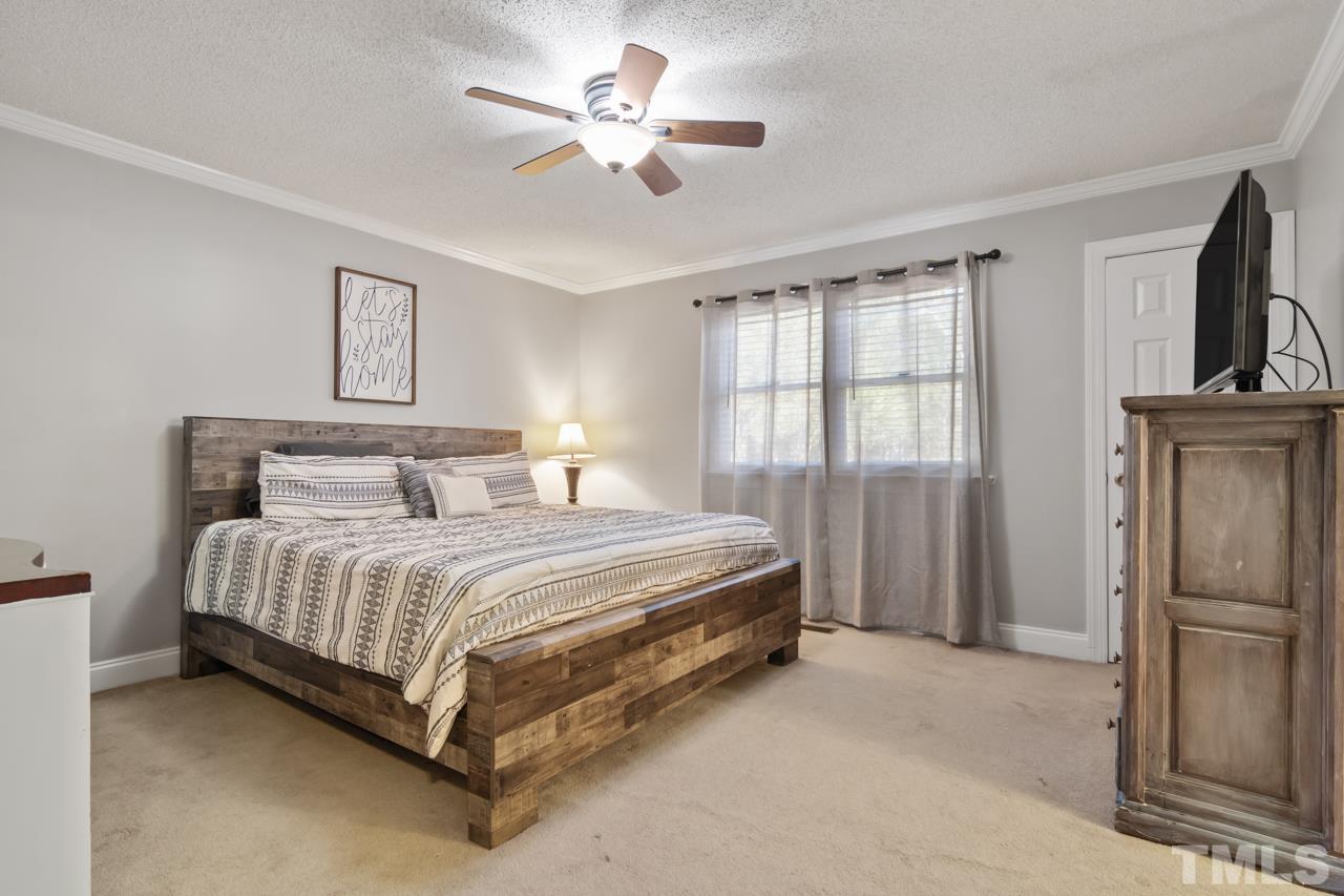6908 Kiger Road Rougemont, NC 27572 - Photo 19 of 30 a spacious bedroom with a bed and a chandelier