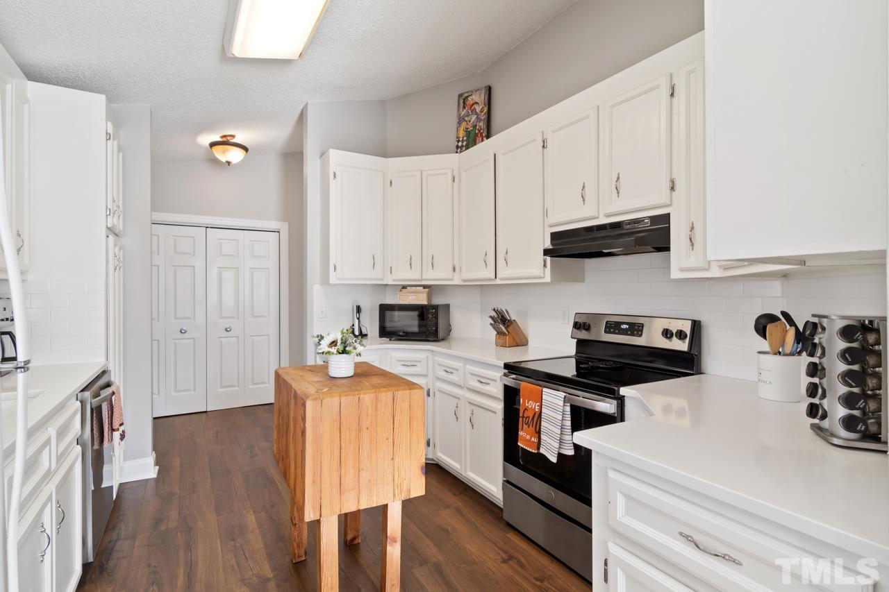 6908 Kiger Road Rougemont, NC 27572 - Photo 6 of 30 a kitchen with stainless steel appliances granite countertop a stove top oven a sink a refrigerator white cabinets and wooden floor