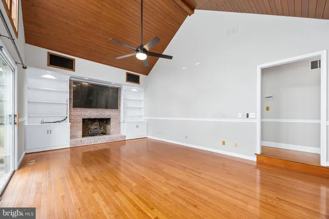 a view of an empty room with window and wooden floor