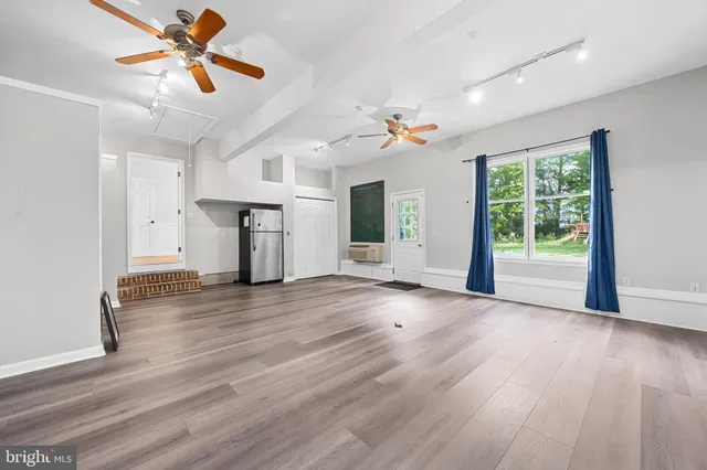 a view of an empty room with a window and wooden floor