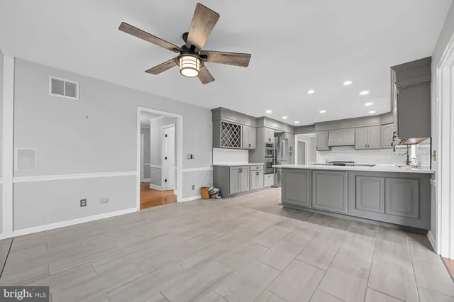 a view of an empty room with a window and a kitchen area