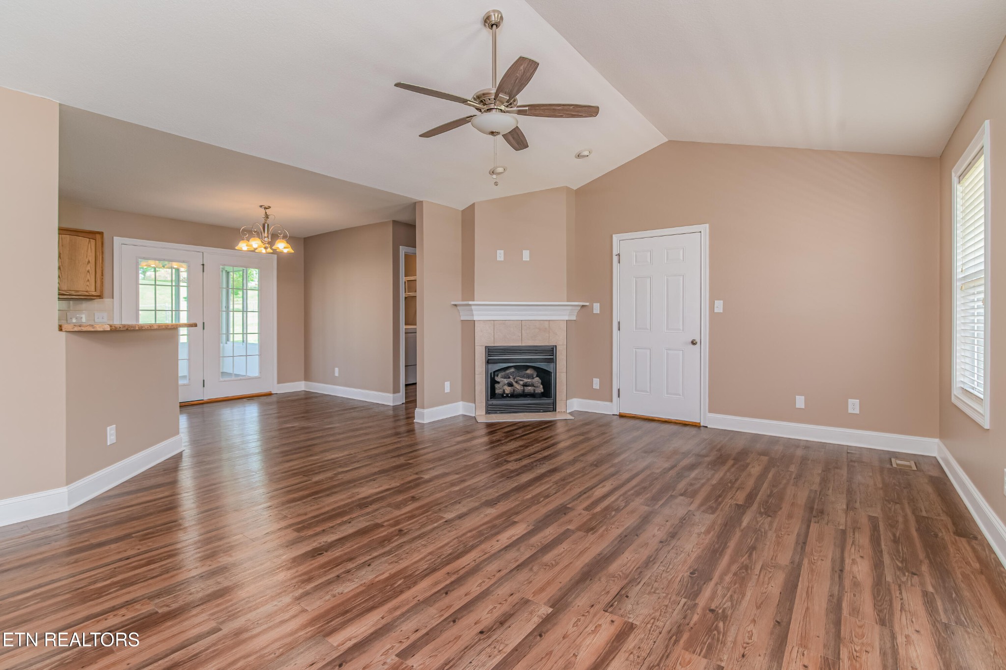 8007 Tazewell Pike Corryton, TN 37721 - Photo 4 of 43 an empty room with wooden floor a ceiling fan a fireplace and windows