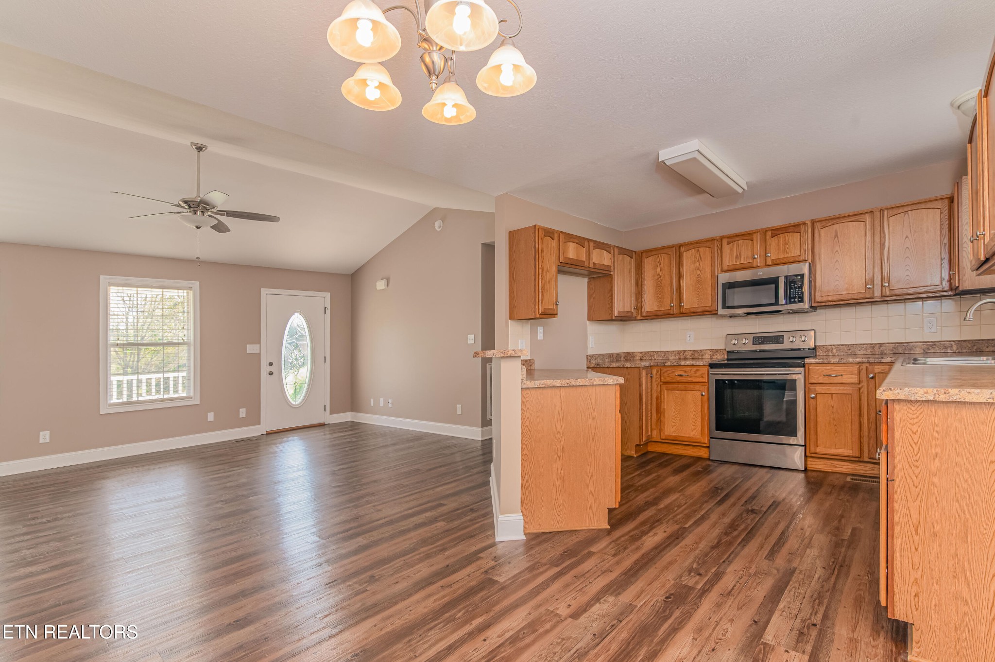 8007 Tazewell Pike Corryton, TN 37721 - Photo 10 of 43 a kitchen with granite countertop a stove top oven a sink dishwasher and a refrigerator with wooden floor