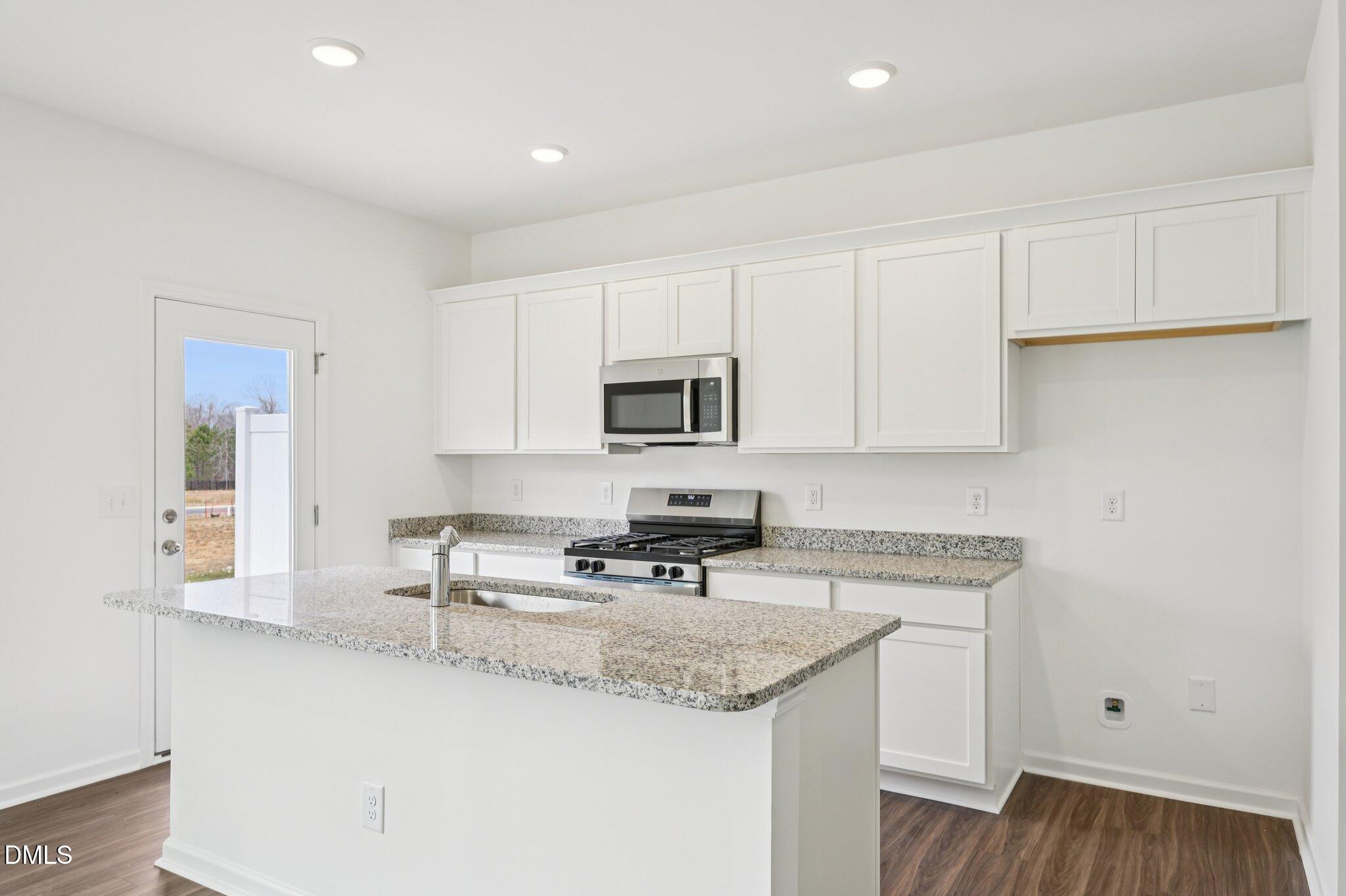 1610 Mirth Court Rolesville, NC 27571 - Photo 11 of 36 a kitchen with granite countertop white cabinets sink and stainless steel appliances