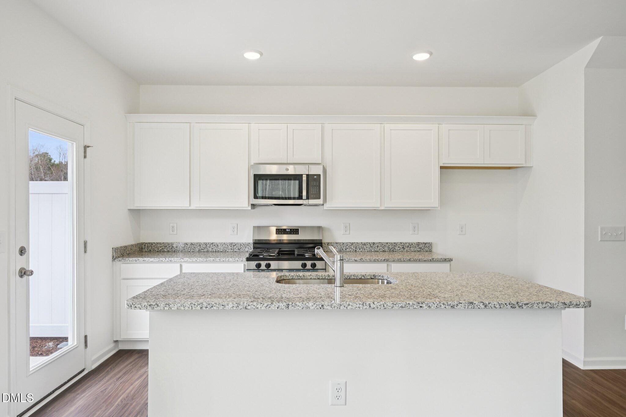 1610 Mirth Court Rolesville, NC 27571 - Photo 12 of 36 a kitchen with granite countertop a sink a stove a washer and dryer