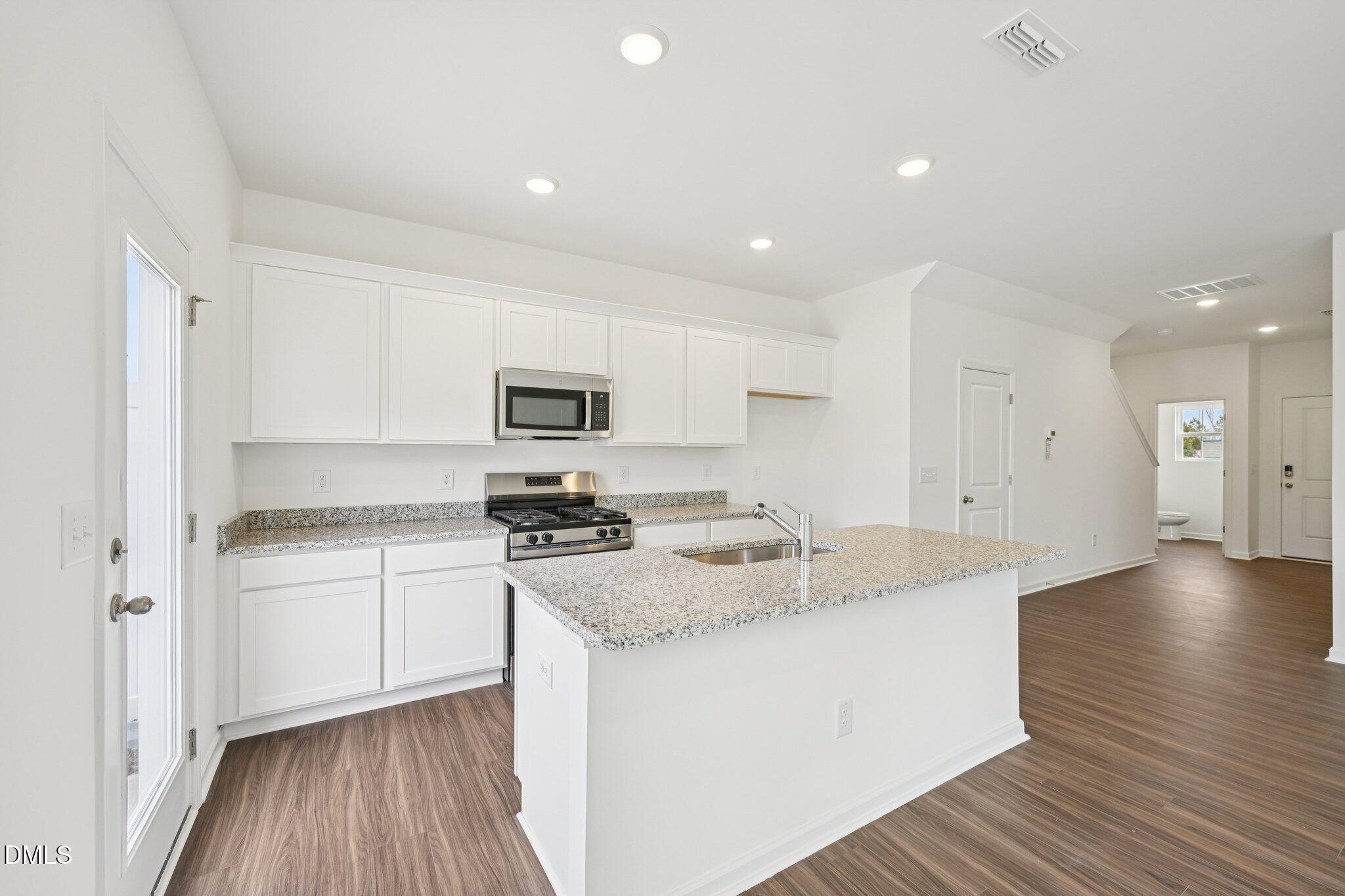 1610 Mirth Court Rolesville, NC 27571 - Photo 13 of 36 a kitchen with stainless steel appliances granite countertop a sink stove refrigerator and white cabinets with wooden floor