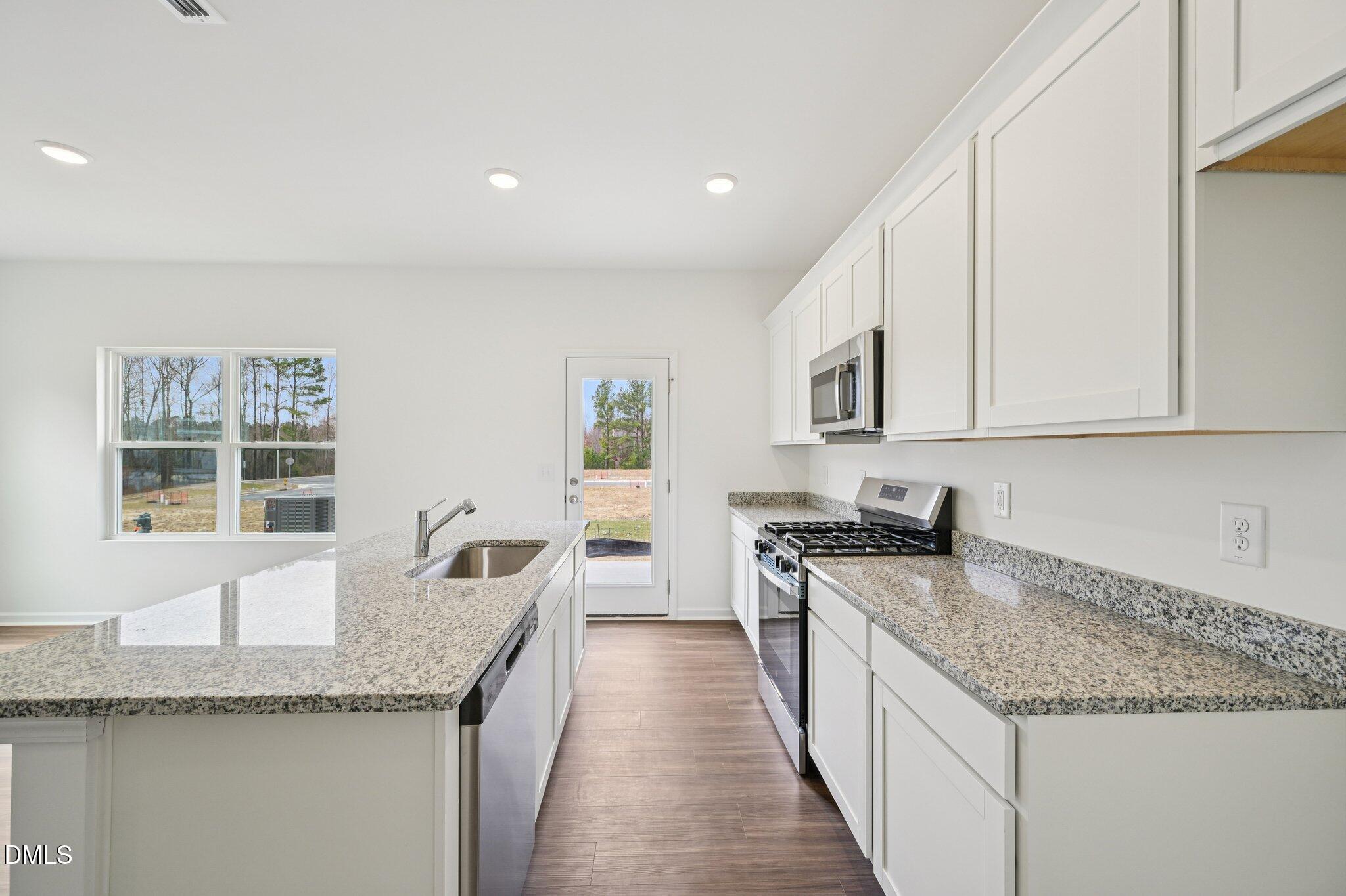 1610 Mirth Court Rolesville, NC 27571 - Photo 14 of 36 a kitchen with granite countertop stainless steel appliances a sink stove and cabinets