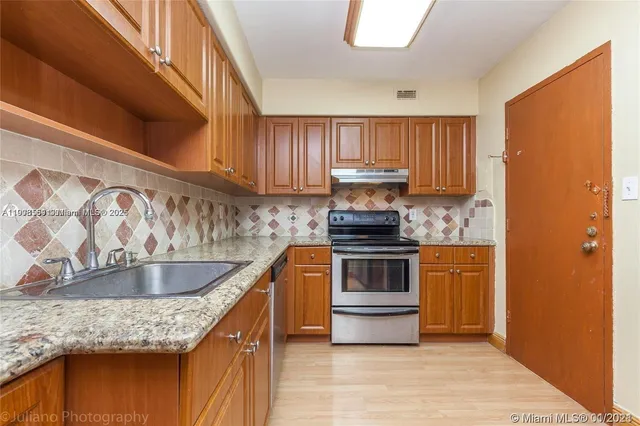 a kitchen with stainless steel appliances granite countertop a sink stove and cabinets