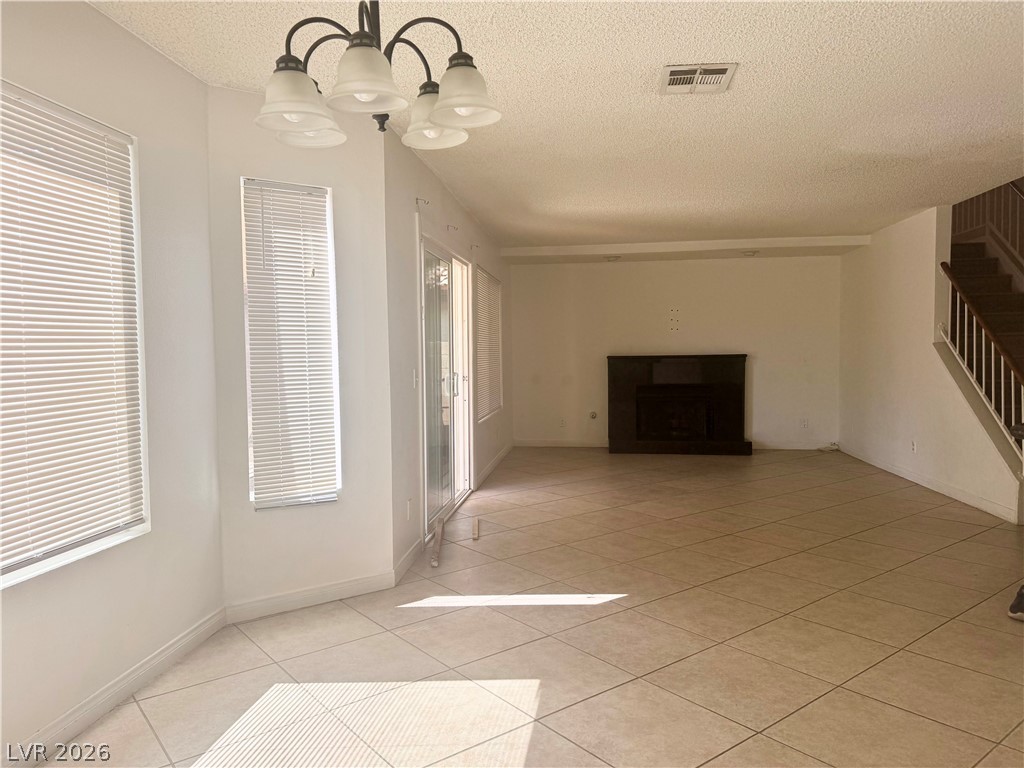135 Primero Way Henderson, NV 89074 - Photo 5 of 15 A spacious living area with ceramic tile flooring, a dark fireplace, and a striking chandelier.