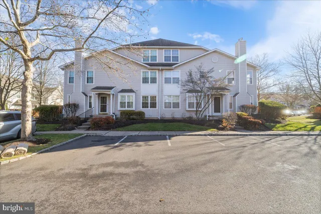 a view of a white house next to a yard with plants and trees