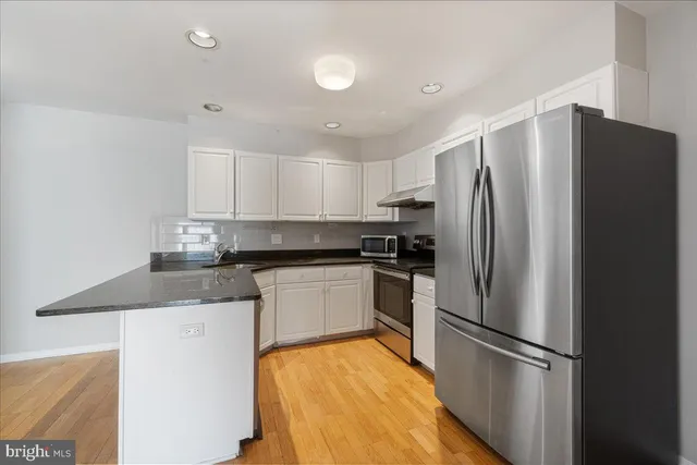 a view of an empty room with wooden floor and stairs