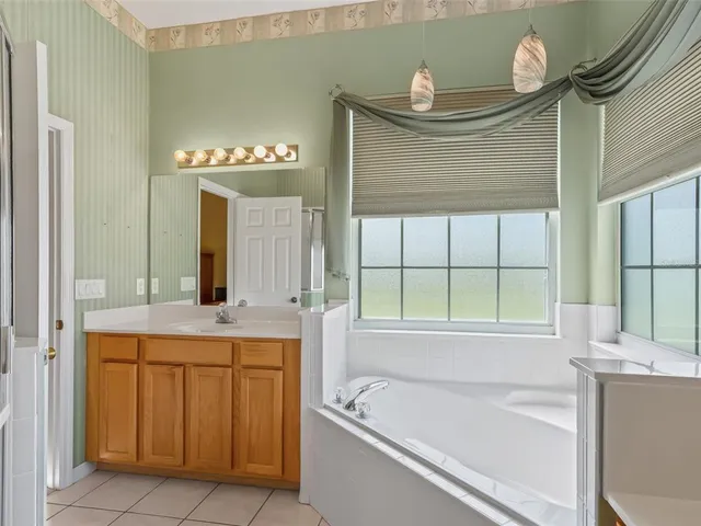 a bathroom with a tub a sink and a large mirror