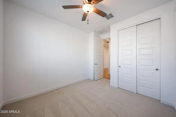 an empty room with closet and a chandelier fan