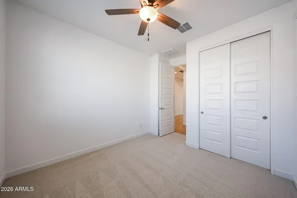 an empty room with closet and a chandelier fan