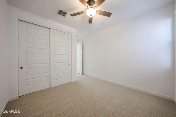 an empty room with closet and fan