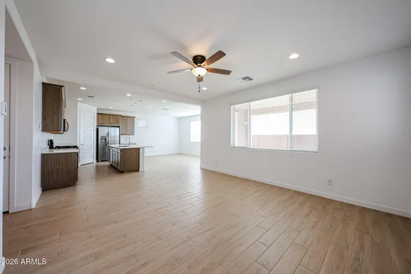 a view of an empty room with a kitchen and wooden floor