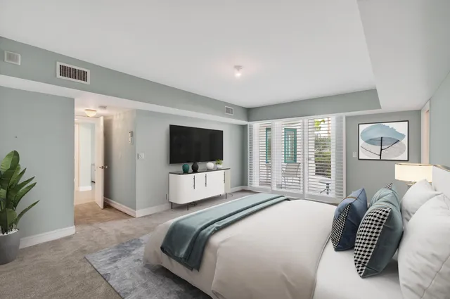 a bedroom with a bed a large window and a flat screen television