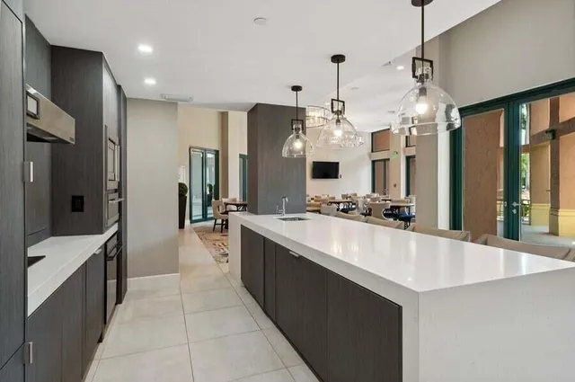 a large white kitchen with a large counter top stainless steel appliances and chandelier