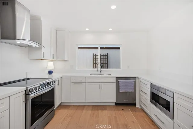 a kitchen with stainless steel appliances a sink cabinets and wooden floor
