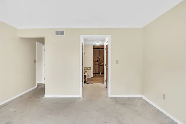 a view of an empty room with closet and wooden door