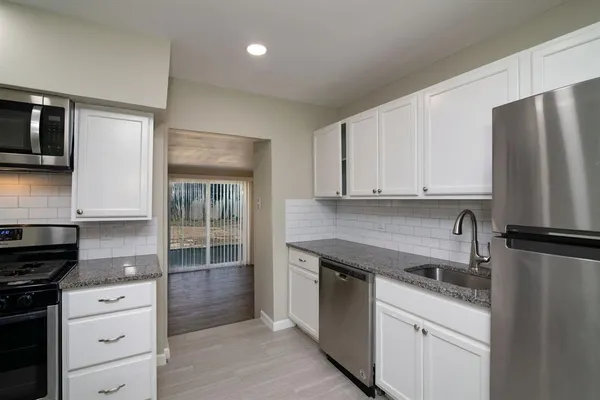 a kitchen with granite countertop a refrigerator stove and sink