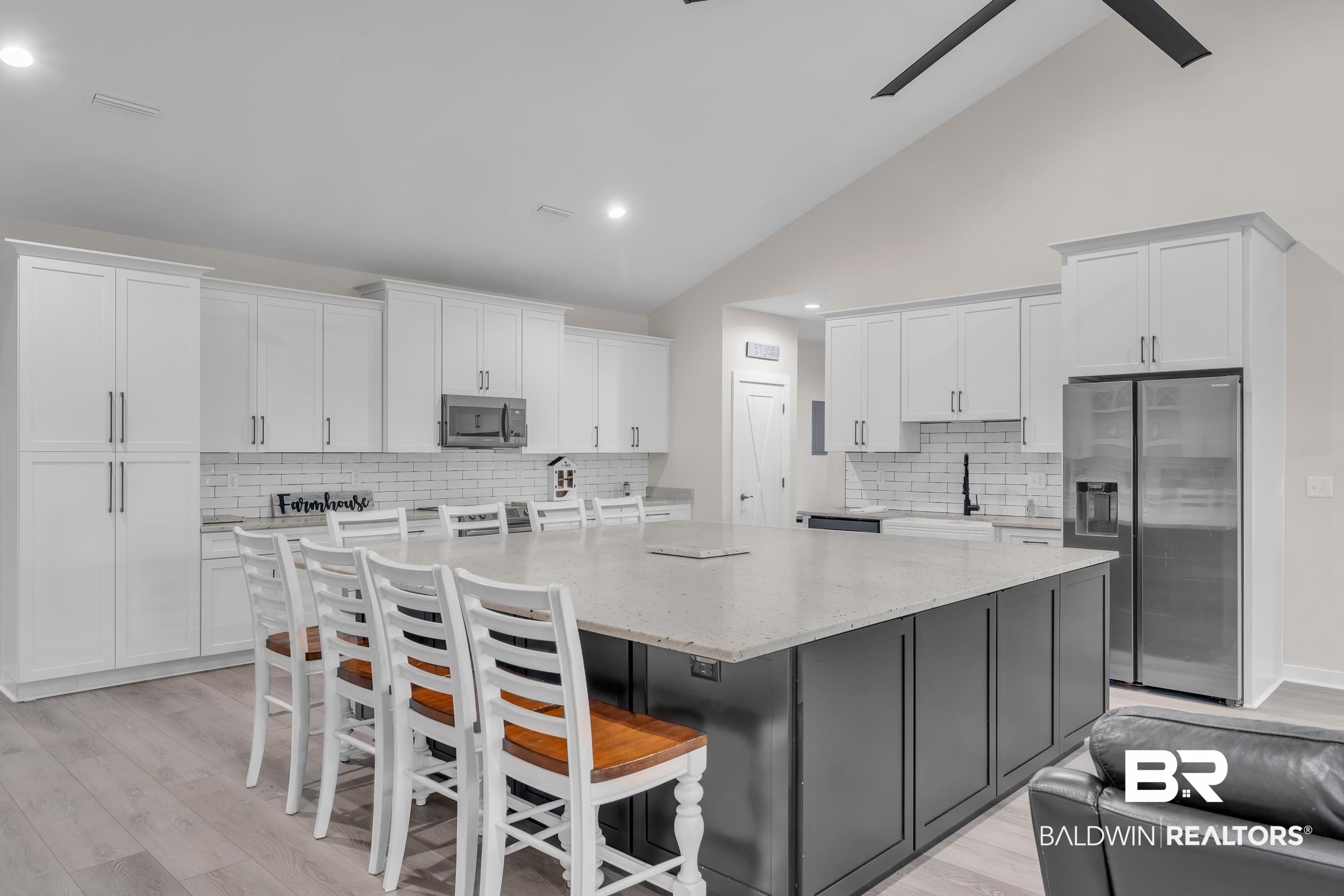 22592 Pastoral Lane Foley, AL 36535 - Photo 8 of 45 Kitchen with appliances with stainless steel finishes, white cabinetry, a large island, backsplash, and high vaulted ceiling