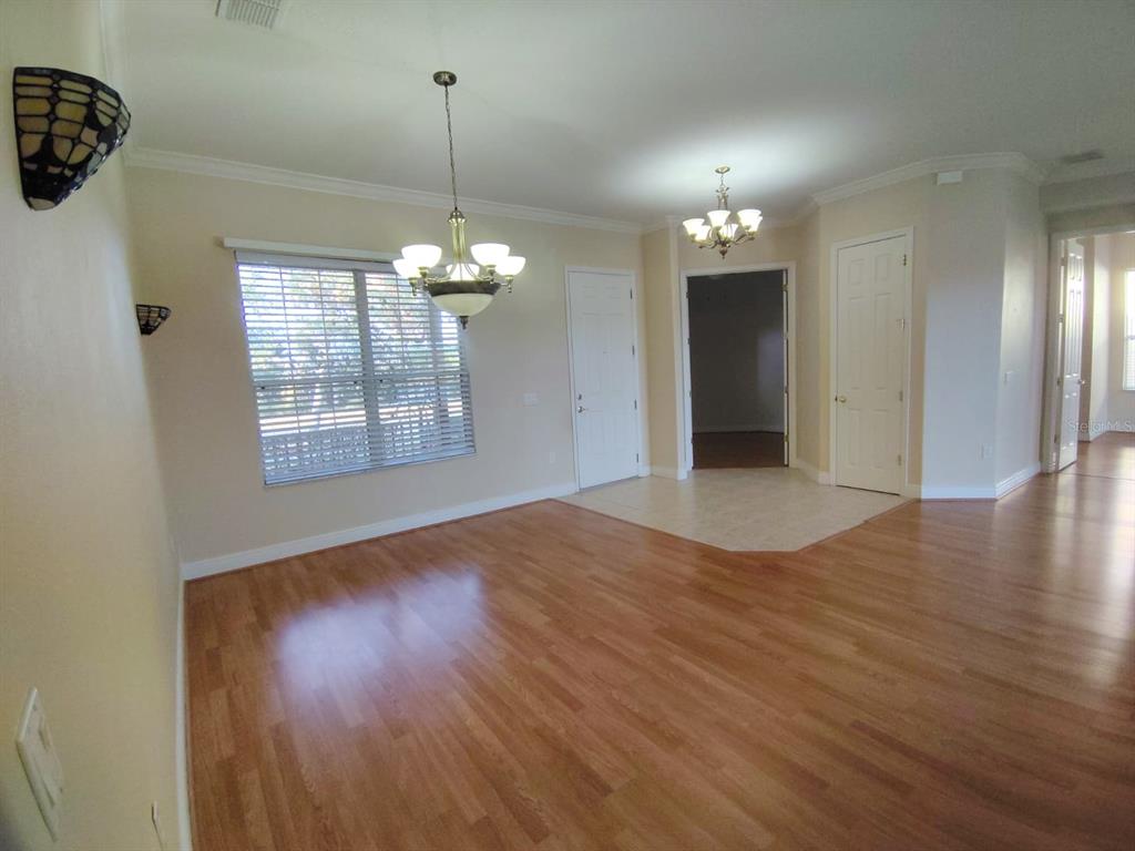 843 Glendora Road Poinciana, FL 34759 - Photo 3 of 15 an empty room with wooden floor chandelier and windows